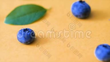 粉红色背景上的蓝莓和绿叶。 电影蓝莓4k视频.. 成熟和多汁的新鲜采摘的蓝莓接近